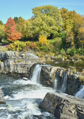 Vibrant orange, yellow, red and green fall colors on trees near waterfall