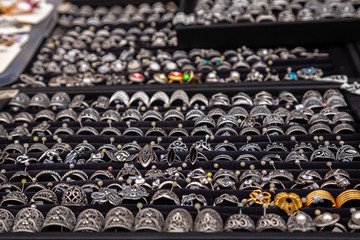 Fototapeta premium Silver rings with precious stones at the jewelry market exhibition. Selective focus. Silver rings and jewelry on a counter in a store.