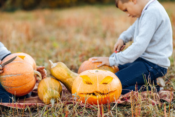 Children playing with pumpkin in autumn Park on Halloween. Boy carving pumpkins