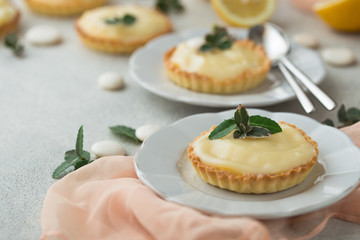Lemon curd tart served with green leaves and lemon. Tartalets, lemon curd tarts