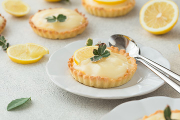 Lemon curd tart served with green leaves and lemon. Tartalets, lemon curd tarts