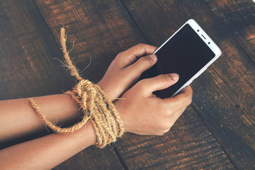 Hands tied by strong rope with mobile - obrazy, fototapety, plakaty