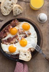 Full American Breakfast on white, top view, copy space. Sunny side fried eggs, roasted bacon