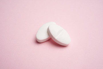 White pills on pink background