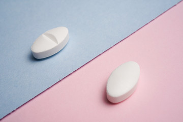 Top view of various white pills on blue and pink background