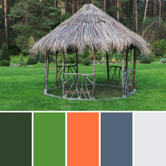 Fototapeta na wymiar Round open arbor from dry branches and straw in a green park on a bright summer day after rain, with a palette of colors