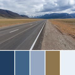 The gray asphalt road goes far and abuts against blue-blue clouds and mountains on a cloudy autumn...