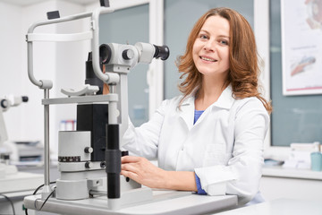 Female oculist checking eyesight with slit lamp in clinic