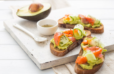sandwich with avocado and salmon on a light background, green onions and gluten-free grain bread, radishes and cucumbers. concept diet food, copy space, sandwich take away, healthy fast food