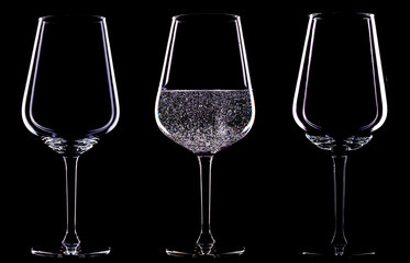 Glasses on a black background, studio, in one glass sparkling wine with bubbles.