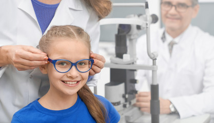 Front view of girl wearing new glasses in optical store