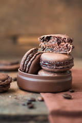Chocolate macaroons with coffee beans close up on wooden table.
