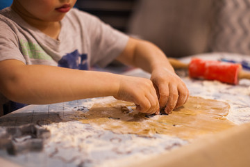 a child cuts a gingerbread cookie with a cookie cutter on New Year's Eve