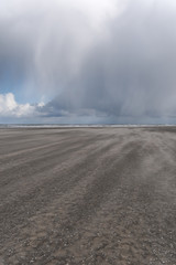 Wetterwechsel am Strand mit Wind, Regen und dunkle Wolken am Kijkduin Strand bei Den Haag, Holland, Niederlande