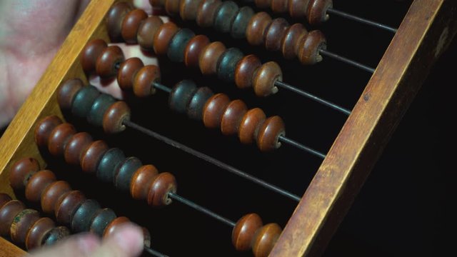 Vintage wooden abacus. Part of the old end of the abacus on a dark background.