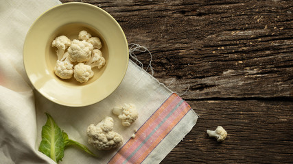 Cooking Cauliflower. Top view, wooden table.In a plate are slices of cabbage