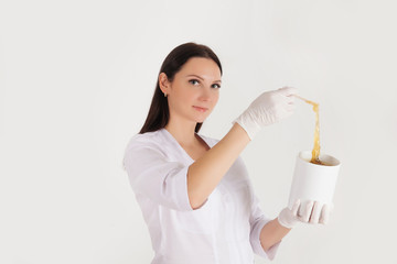Depilation and hair removal concept. Mockup free space for text. Beautiful female doctor in medical gown uniform with sugar paste