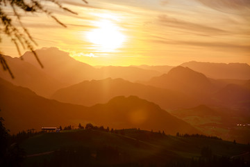 Sunset in the Austrian Alps - panorama view from Donnerkogel, with layers of mountains peaks and ridges glowing in the warm evening light.