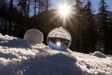 lens ball during winter in austria europa, crystal ball in the snow with an amazing sunset in the...