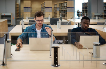 Young men working on a laptops in public library