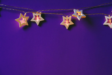 Illuminated star shaped garland on color background close up