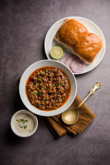 Kheema / keema Pav or Khima Paav is a spicy curry dish made up of minced chicken or lamb cooked with onion, tomatoes, served with buns. selective focus