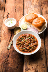 Kheema / keema Pav or Khima Paav is a spicy curry dish made up of minced chicken or lamb cooked with onion, tomatoes, served with buns. selective focus