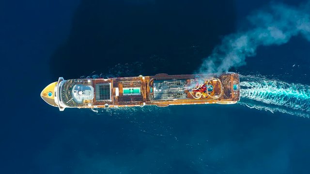 Cruise ship liner sails in the blue sea leaving a plume on the surface of the water seascape, aerial view of sea travel, cruises