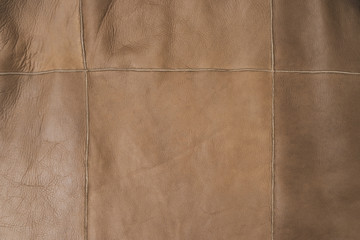 Brown leather surface stitched with threads. Natural material sample. Textured colorful background. Free space for advert.
