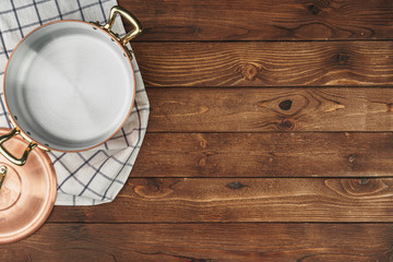 New copper cooking pot on wooden table, view from above