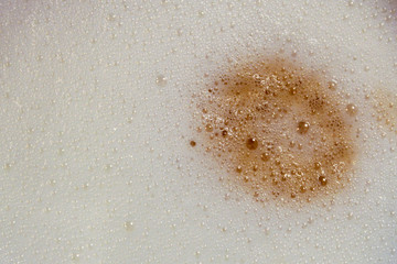 White  cappuccino coffee foam with a brown stain and bubbles