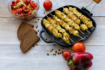chicken skewers in a pan with pepper salad and tomato and spices