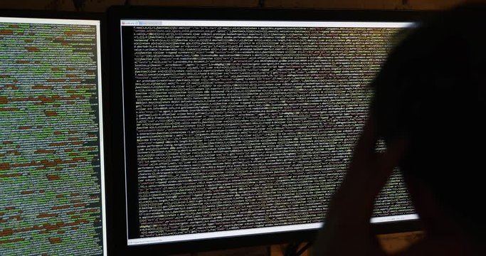 programmer working in dark room. scrolling code on computer screen