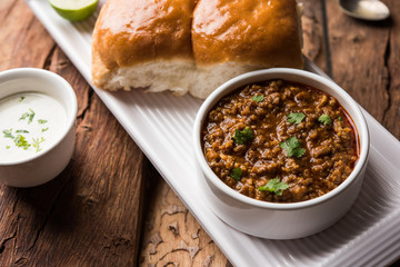 Kheema / keema Pav or Khima Paav is a spicy curry dish made up of minced chicken or lamb cooked with onion, tomatoes, served with buns. selective focus