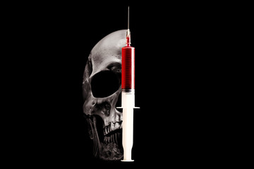 Skull and syringe with red liquid on a black background. The concept of drug addiction.