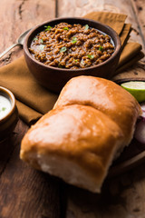 Kheema / keema Pav or Khima Paav is a spicy curry dish made up of minced chicken or lamb cooked with onion, tomatoes, served with buns. selective focus