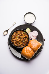 Kheema / keema Pav or Khima Paav is a spicy curry dish made up of minced chicken or lamb cooked with onion, tomatoes, served with buns. selective focus