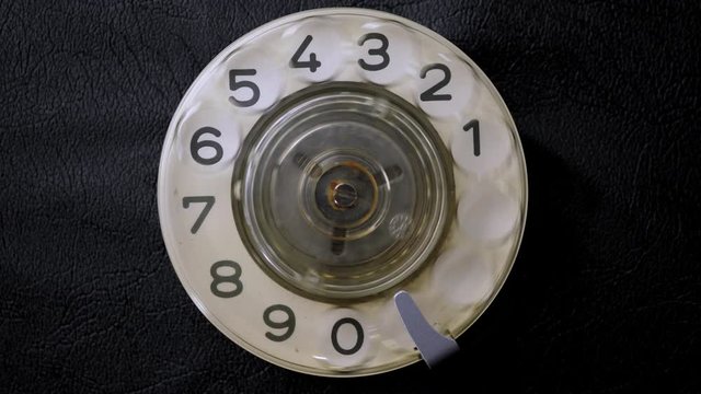 Dialing on an old rotary style telephone. Close-up view.