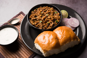 Kheema / keema Pav or Khima Paav is a spicy curry dish made up of minced chicken or lamb cooked with onion, tomatoes, served with buns. selective focus