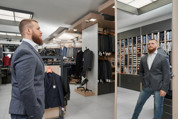 Man in jacket keeping hand in glove and looking at mirror