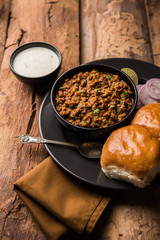 Kheema / keema Pav or Khima Paav is a spicy curry dish made up of minced chicken or lamb cooked with onion, tomatoes, served with buns. selective focus