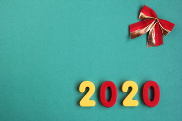 2020 new year numbers and a red bow on a green background. Empty space for text.