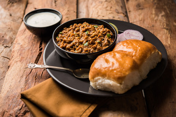 Kheema / keema Pav or Khima Paav is a spicy curry dish made up of minced chicken or lamb cooked with onion, tomatoes, served with buns. selective focus