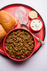 Kheema / keema Pav or Khima Paav is a spicy curry dish made up of minced chicken or lamb cooked with onion, tomatoes, served with buns. selective focus