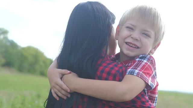 happy family. mom and son happiness love teamwork concept. gentle lifestyle touching slow motion video. son little boy hugs mom girls outdoors. happy family blond a boy and mom brunette