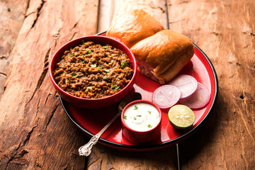Kheema / keema Pav or Khima Paav is a spicy curry dish made up of minced chicken or lamb cooked with onion, tomatoes, served with buns. selective focus