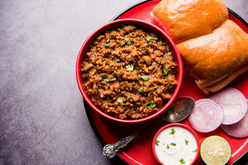 Kheema / keema Pav or Khima Paav is a spicy curry dish made up of minced chicken or lamb cooked with onion, tomatoes, served with buns. selective focus