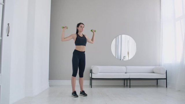 Raise the dumbbells over your head performing exercises for the shoulders. Training at home in the apartment