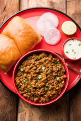 Kheema / keema Pav or Khima Paav is a spicy curry dish made up of minced chicken or lamb cooked with onion, tomatoes, served with buns. selective focus