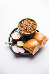 Kheema / keema Pav or Khima Paav is a spicy curry dish made up of minced chicken or lamb cooked with onion, tomatoes, served with buns. selective focus